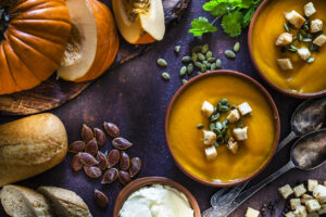 Pumpkin soup with ingredients on rustic brown table. Top view