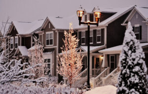 Front yard, townhouses and beautiful, illuminated by lamps trees under fresh snow.