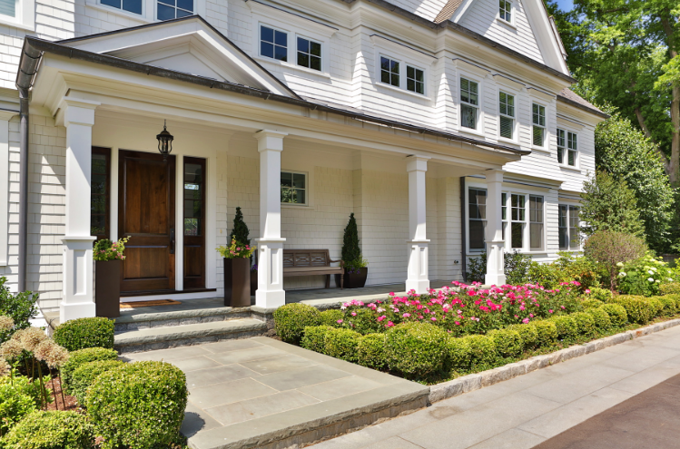 Front door of house with large flower beds