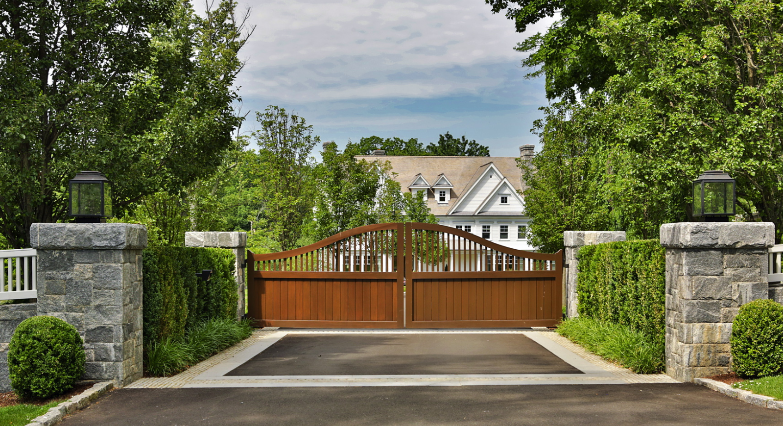 Wooden gate at the front of a home with two stone pillars next to it