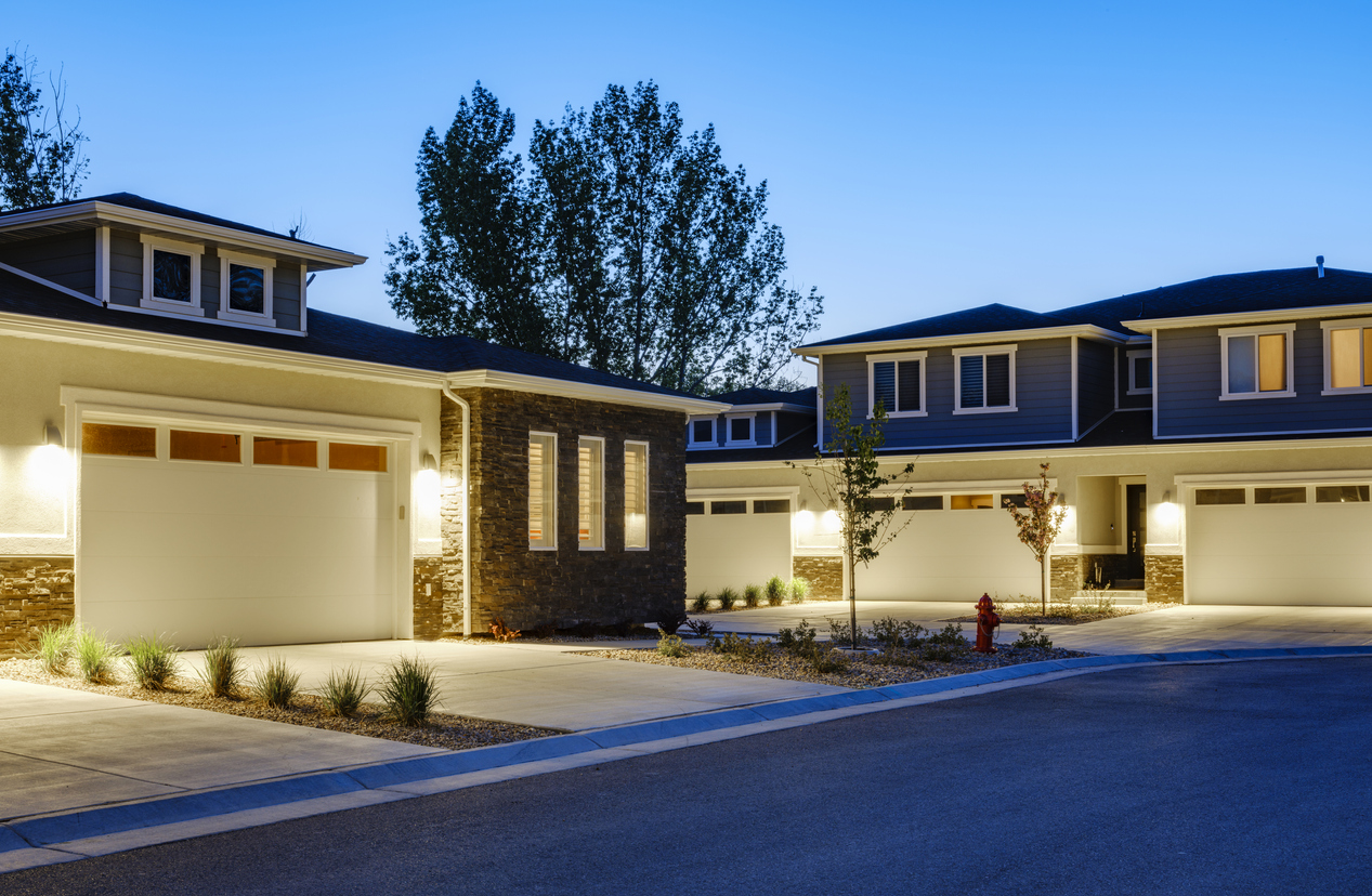 A suburban USA neighborhood at dusk with exterior lights on.