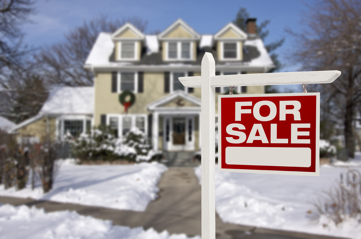 Home For Sale Real Estate Sign in Front of Beautiful New House in the Snow.