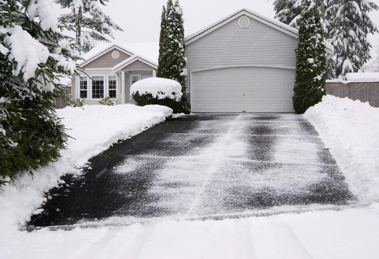 A new round of snow begins covering a recently shoveled driveway. Slow shutter speed to emphasize motion of the falling snow.