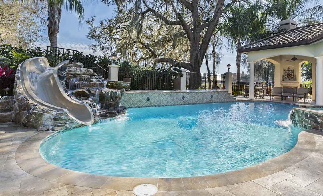 A backyard swimming pool with a waterfall and slide