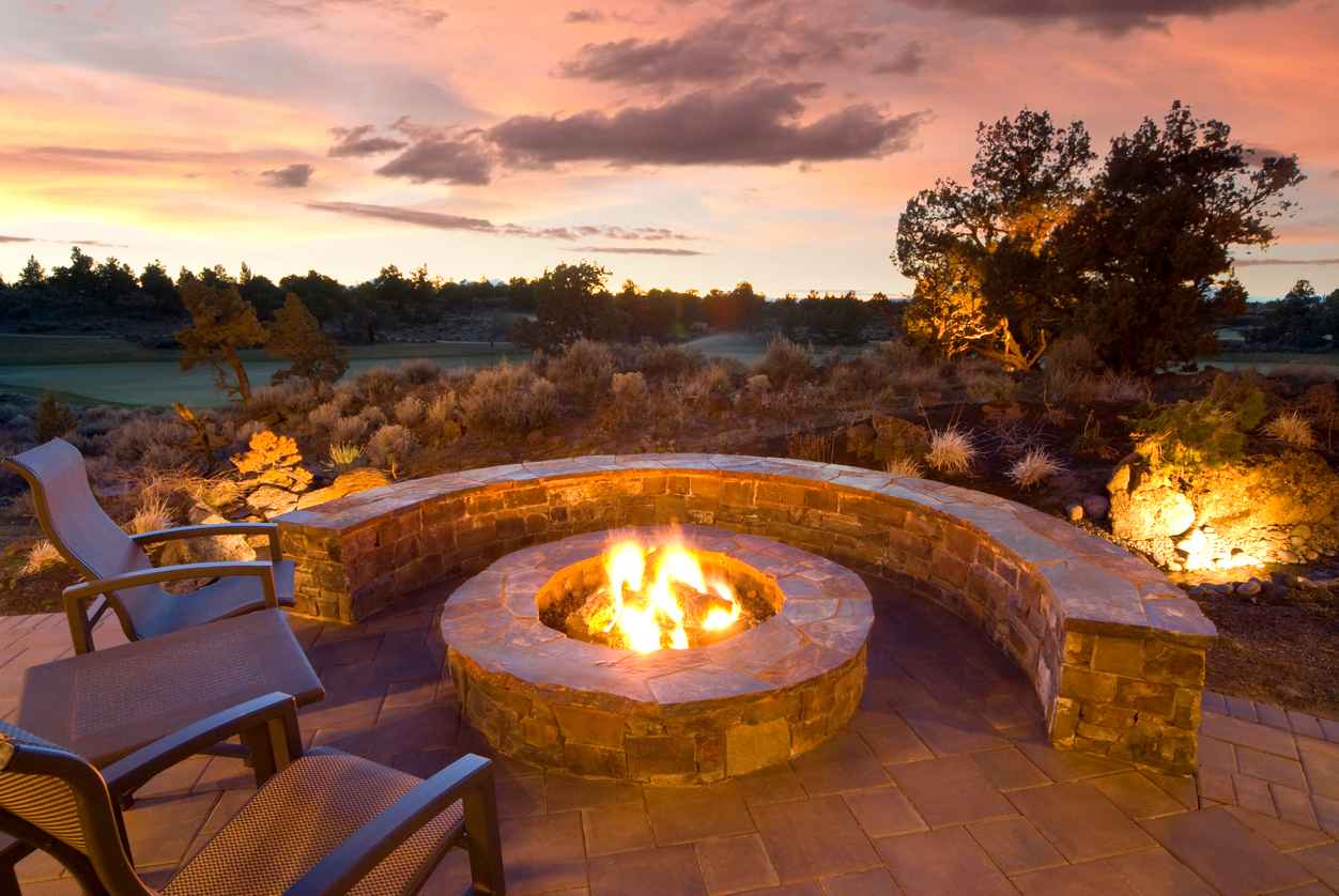 stone fire pit with outdoor chairs, enjoying the sunset and landscape; 2024 landscape design trends