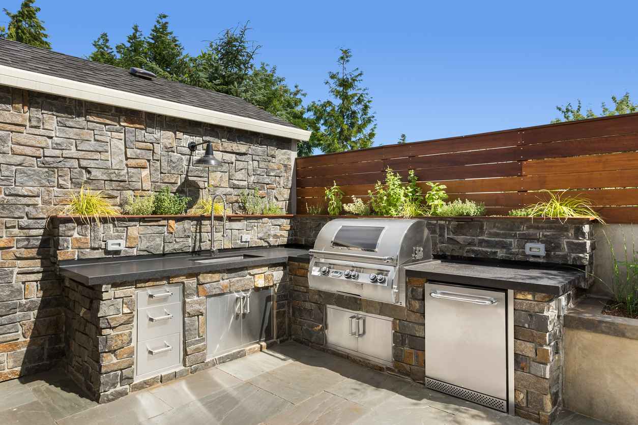 Backyard hardscape entertainment area with outdoor kitchen and greenery