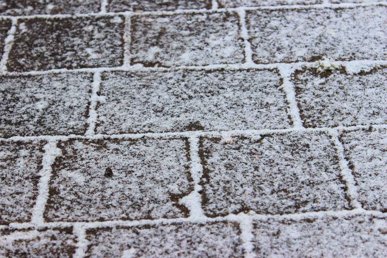 Photo showing a block paved driveway that has just been covered with a light layer of snow in the cold winter months.