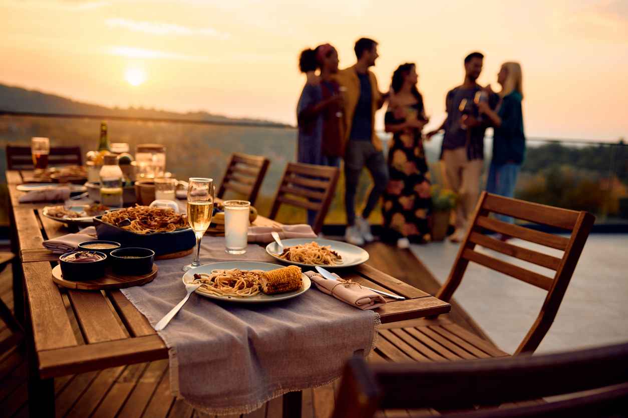 Close up of dining table on a patio at sunset with group of friends in the background.