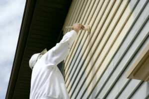 Man in white coveralls painting the outside of a house