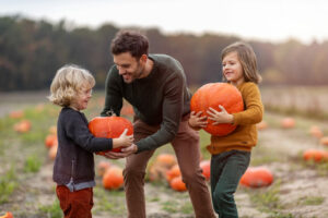 Father and sons in pumpkin patch field