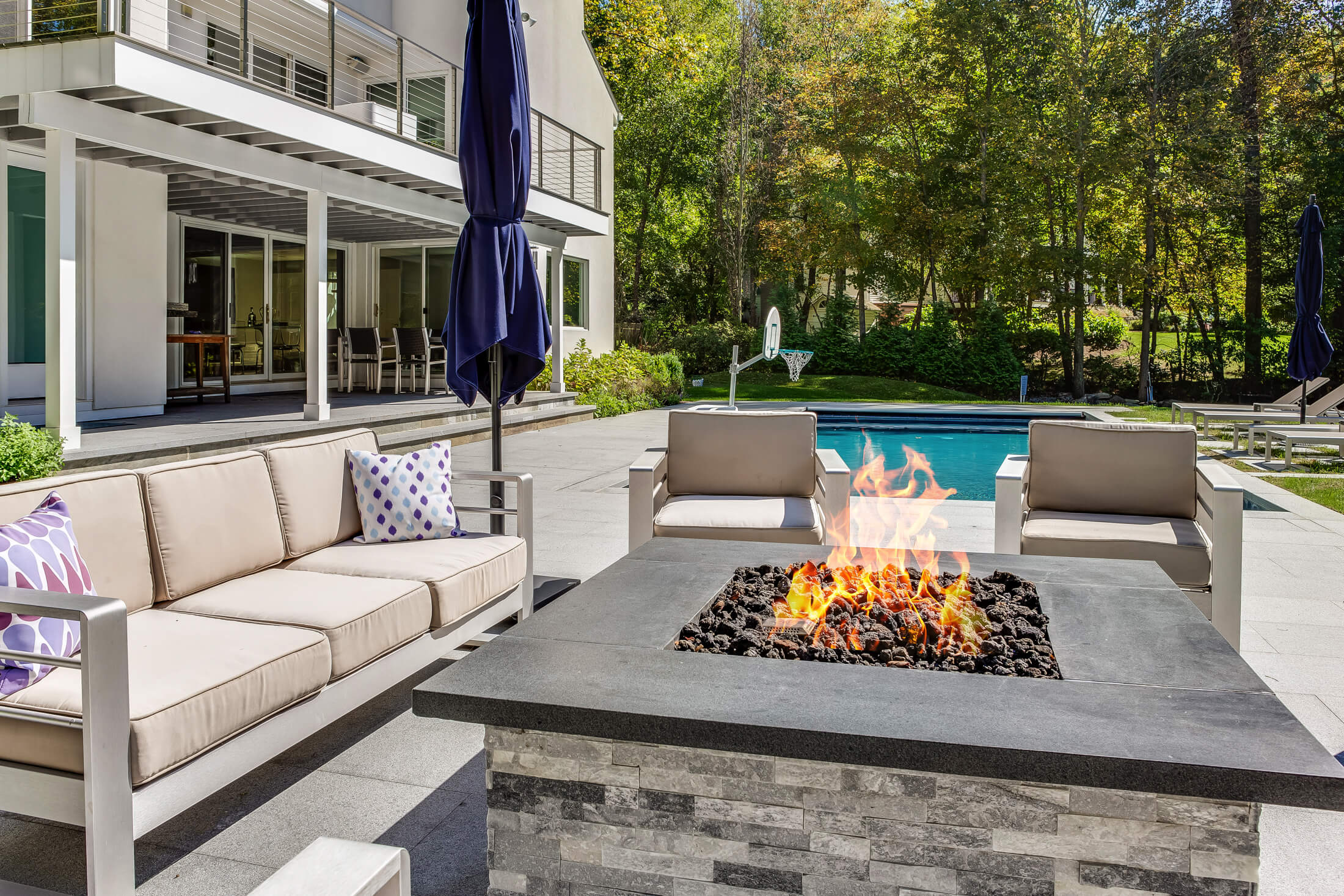 Outdoor seating area with fire pit and pool in background
